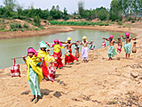 Image 12a: 7 water bearers in curved row by the Nile, volume of water: 132 litres (Scene enacted by the author in 2012 on the river Nahm pa niang in Thailand)